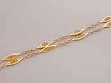 a gold bracelet with a long chain and a leaf design