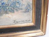 a painting of blue flowers in a gold frame on the wall