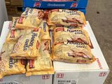 Plusieurs cartons de snacks sont empilés sur une palette dans un magasin.