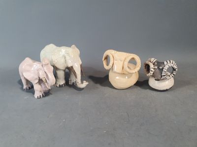 trois petites figurines représentant des éléphants et une girafe, posées sur une surface grise