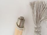 a bottle of perfume next to a brush on a white surface