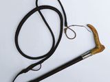 une canne noire avec un manche marron et une corde attachée dessus