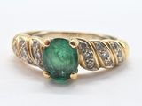 an image of a ring with a green stone surrounded by diamonds