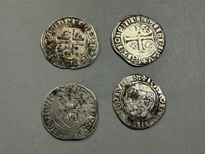 quatre pièces d'argent ornées d'une couronne, posées sur une table