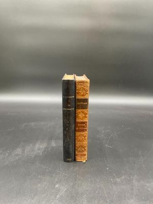 two old books sitting on top of each other on a table