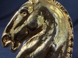 a gold horse head on top of a black stand