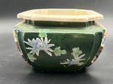 an image of a green vase with flowers on it on a table