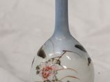 a small blue vase with flowers on it on a white surface
