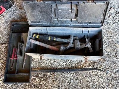 une boîte à outils posée par terre, contenant des outils