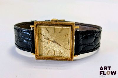 une photo d'une montre en or avec un bracelet en cuir noir