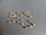 six pairs of gold plated screws on a gray surface