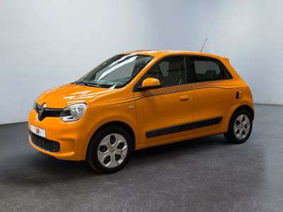 La petite voiture orange est garée dans une grande pièce.