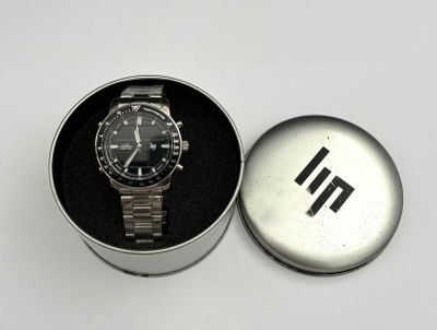 a watch sitting in a metal box on a white surface