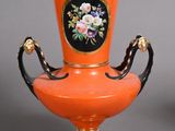 two orange vases with black handles sitting on a table