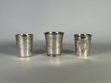trois verres à shot en métal argenté posés sur une table