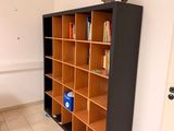 bookshelf in the corner of a room with a table and a chair