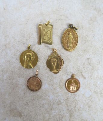 four gold and silver religious charms on a marble surface