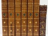 six vieux livres sont alignés sur une surface blanche
