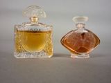 two bottles of perfume sitting next to each other on a table