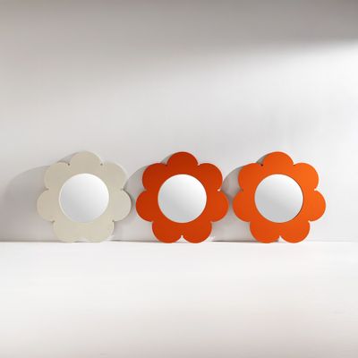 trois miroirs en forme de fleur posés sur une surface blanche
