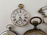 three different types of pocket watches sitting on a table