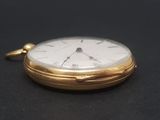 a gold pocket watch with a white face on a black surface