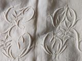 two white embroidered flowers on a white cloth with a black background
