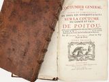 un vieux livre ouvert posé sur une table, à côté d'un autre livre