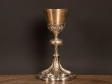 un gobelet ancien en argent posé sur une table en bois, sur fond noir