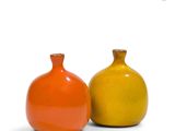 two orange and yellow vases sitting next to each other on a white surface