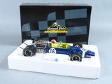 une voiture de course bleue et blanche exposée devant une boîte noire et blanche