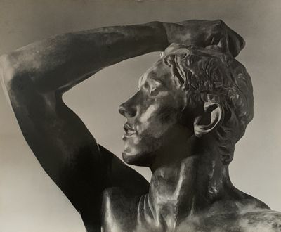 photographie en noir et blanc représentant la statue d'un homme, les mains sur la tête