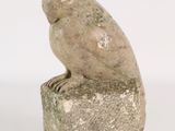 statue of an owl sitting on a rock on a white background