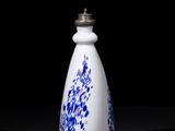 blue and white porcelain bottle with a silver lid on a black surface
