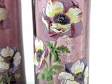 two vases with flowers painted on them on a table