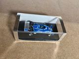 a blue toy car in a clear box on the floor