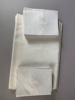 three white napkins with embroidered monograms on them on a table