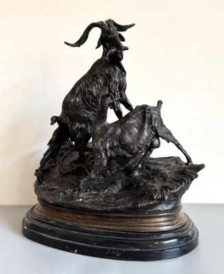 une statue en bronze représentant une chèvre et une chèvre perchée sur un rocher
