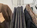 several pairs of clothes hang on a rack in a clothing store