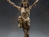 statue en bronze représentant une personne sur une croix, les bras tendus