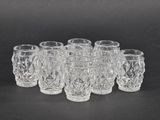 six clear glass shot glasses lined up on a black surface