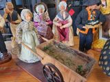 many figurines of people standing around a wheelbarrow