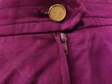 a close up of a purple pants with a gold button on it