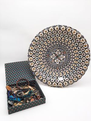 une assiette noire et blanche posée à côté d'une boîte à bijoux