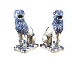 une paire de lions en porcelaine bleue et blanche sur des socles, sur fond blanc