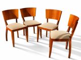 Quatre chaises en bois, dont les assises sont recouvertes d'un tissu beige, sont disposées en cercle.