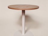 une table ronde avec un piètement blanc et un plateau en bois