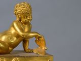 a gold figurine of a baby laying on top of a box