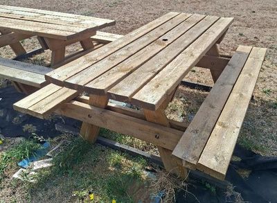 two wooden picnic tables sitting in the grass