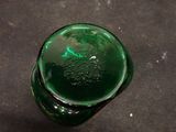 a green glass bottle sitting on a black surface
